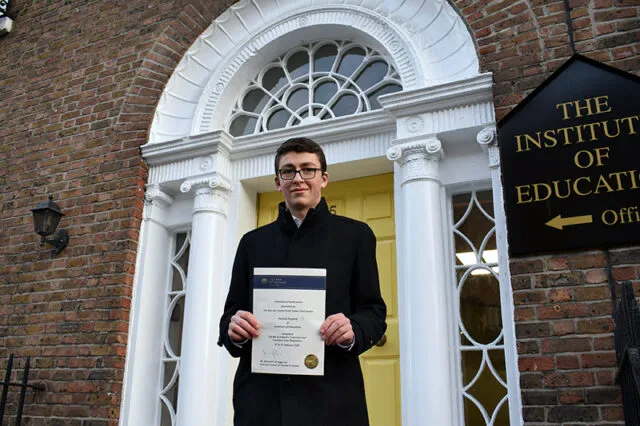 A photograph of Patrick Purfield holding his certificate