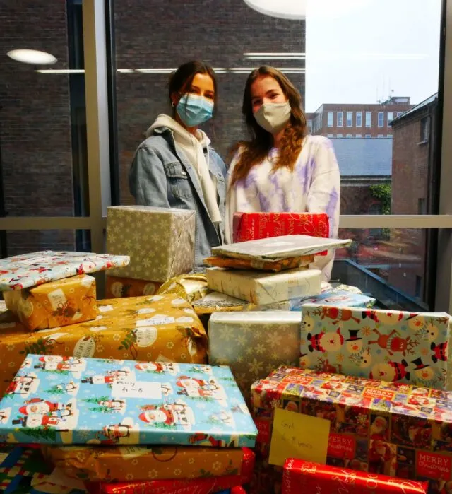 Students posing with wrapped Christmas gifts