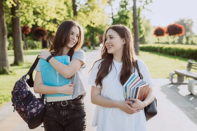 two-happy-smiling-student-girls-are-walking-talking-each-other-campus-warm-sunny-day-soft-selective-focus-scaled-1