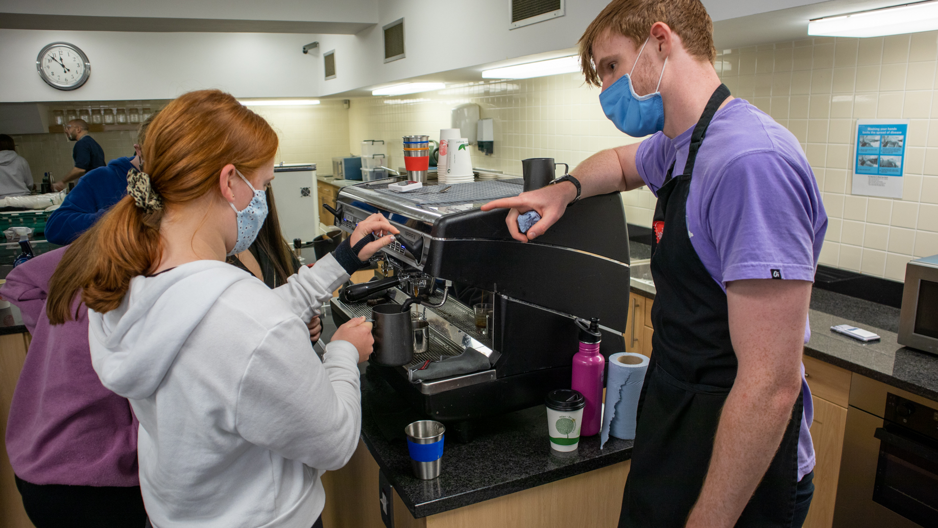 Teacher supervising a student as she uses the coffee machine