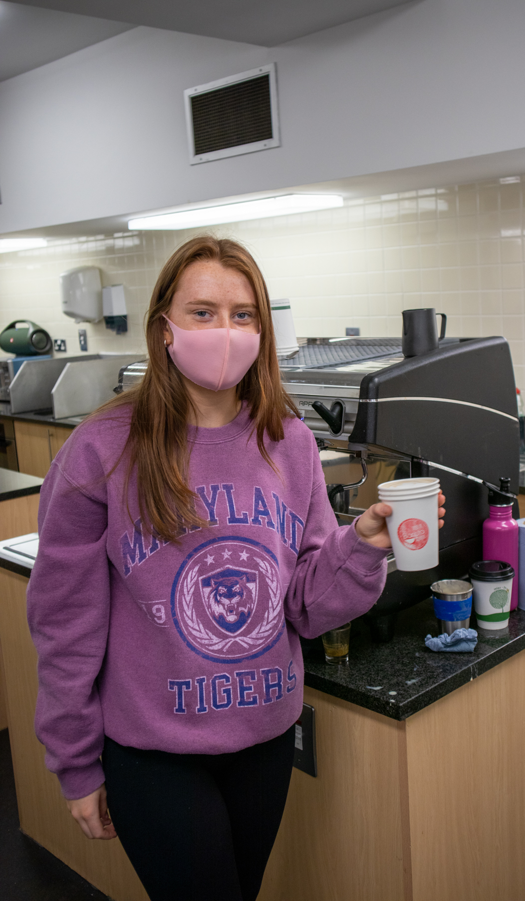 Student holding a cup of coffee she made.