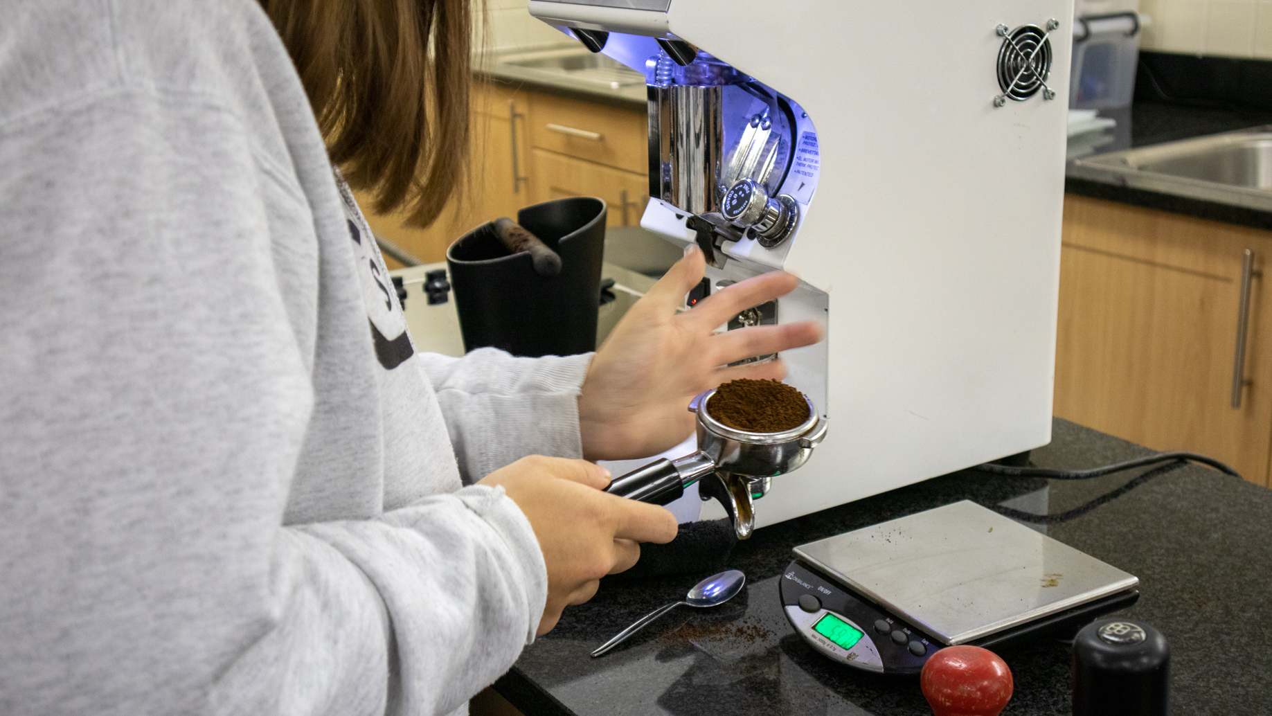 Student tampering down the coffee in the portafilter