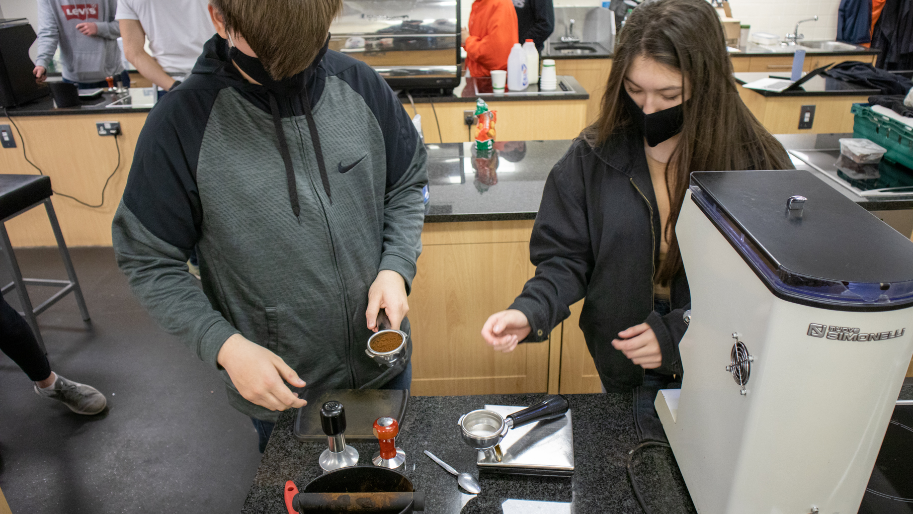 Student holding a portafilter filled with coffee