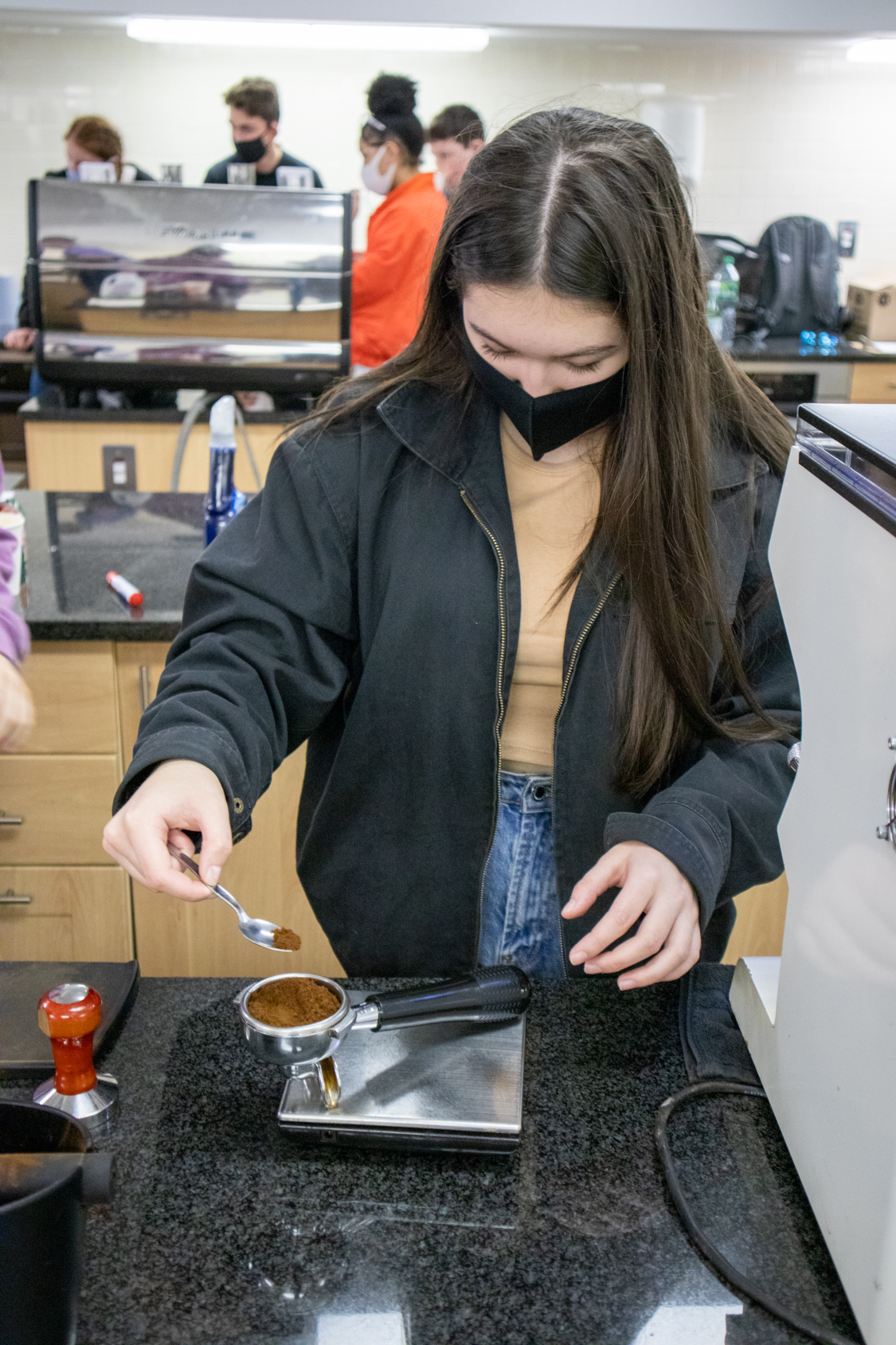 Student packing ground coffee into a portafilter