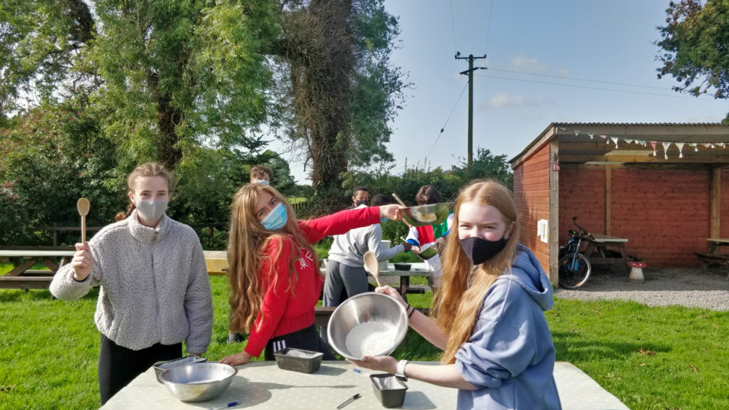 Students posing with mixing bowls and baking spoons