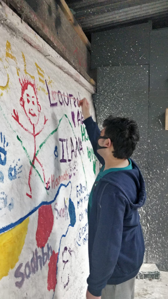 Student writing his name on the wall