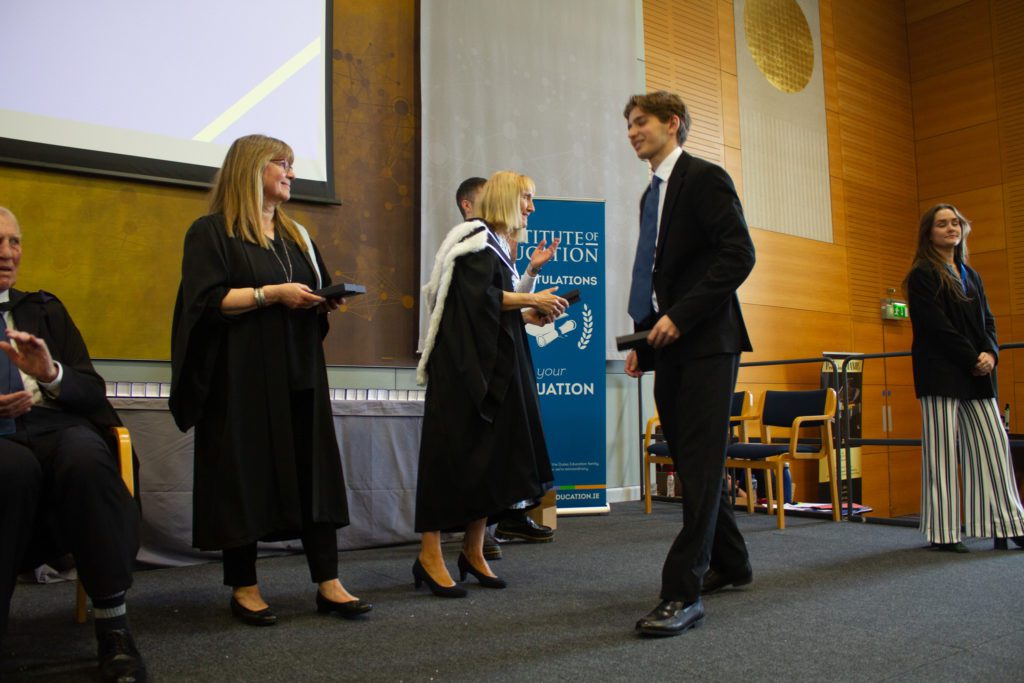 Single student on stage getting handed his qualification