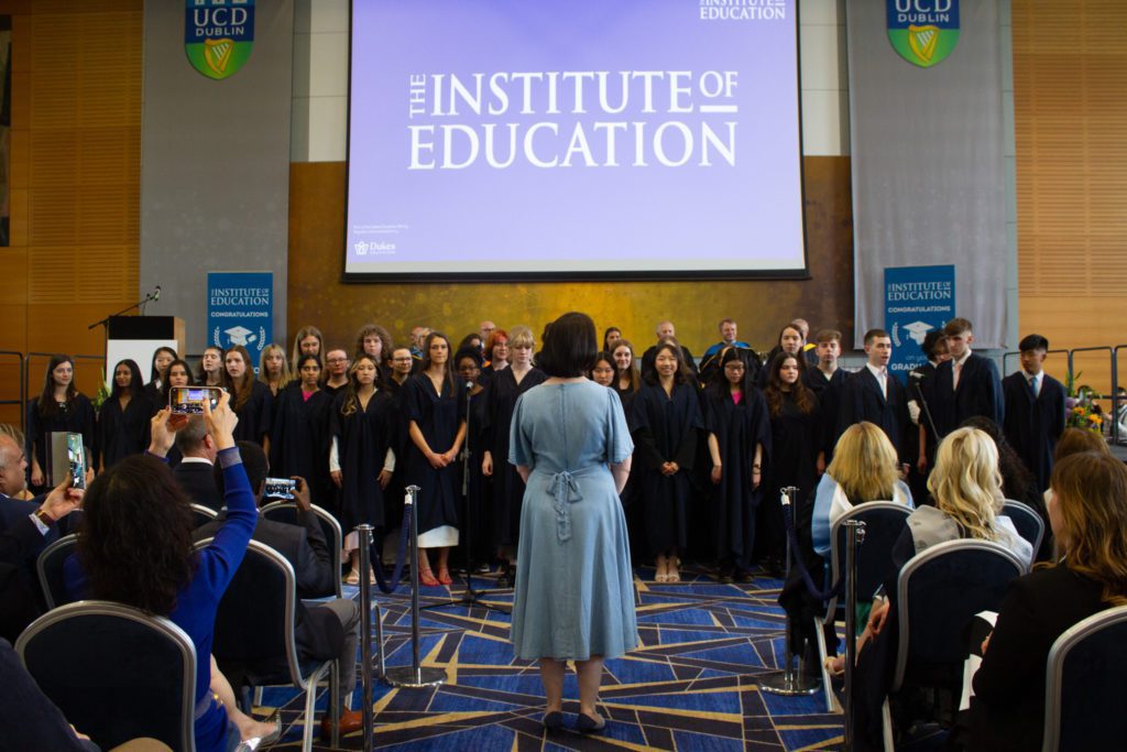 Photo of all of the graduating class, with a teacher stood facing them