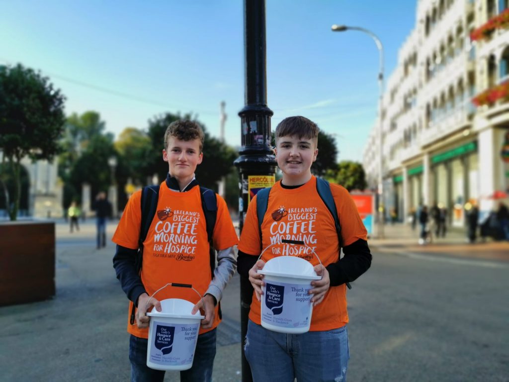 Two students posing with donation buckets