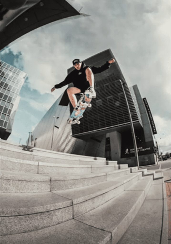 Man skating and jumping down a staircase outside