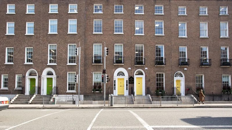 Row of Georgian townhouses on Leeson Street with brick façades and colourful front doors, including two matching yellow doors.