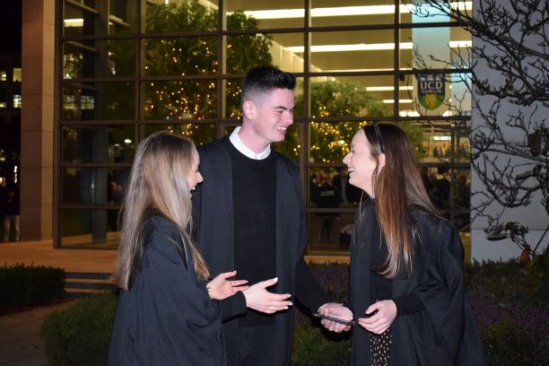 photo of three students, 2 women and a man mid conversation