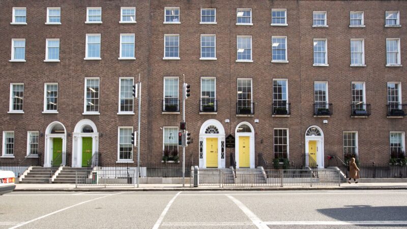 A row of Georgian brick townhouses on a Dublin street, with the Institute of Education's yellow front doors visible among neighbouring green and white doors.