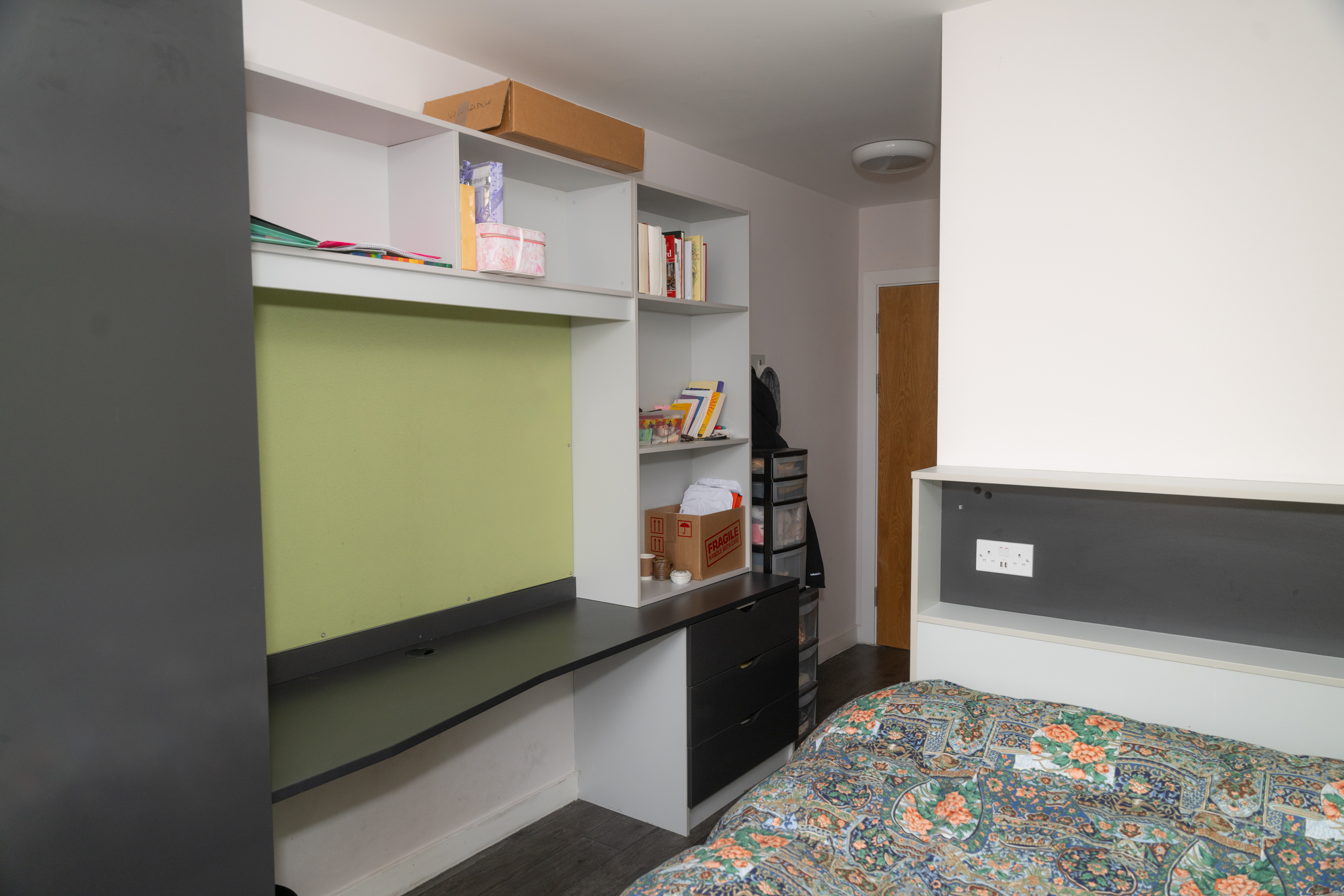 Bedroom: Single bed with green headboard, built-in shelving and desk unit.