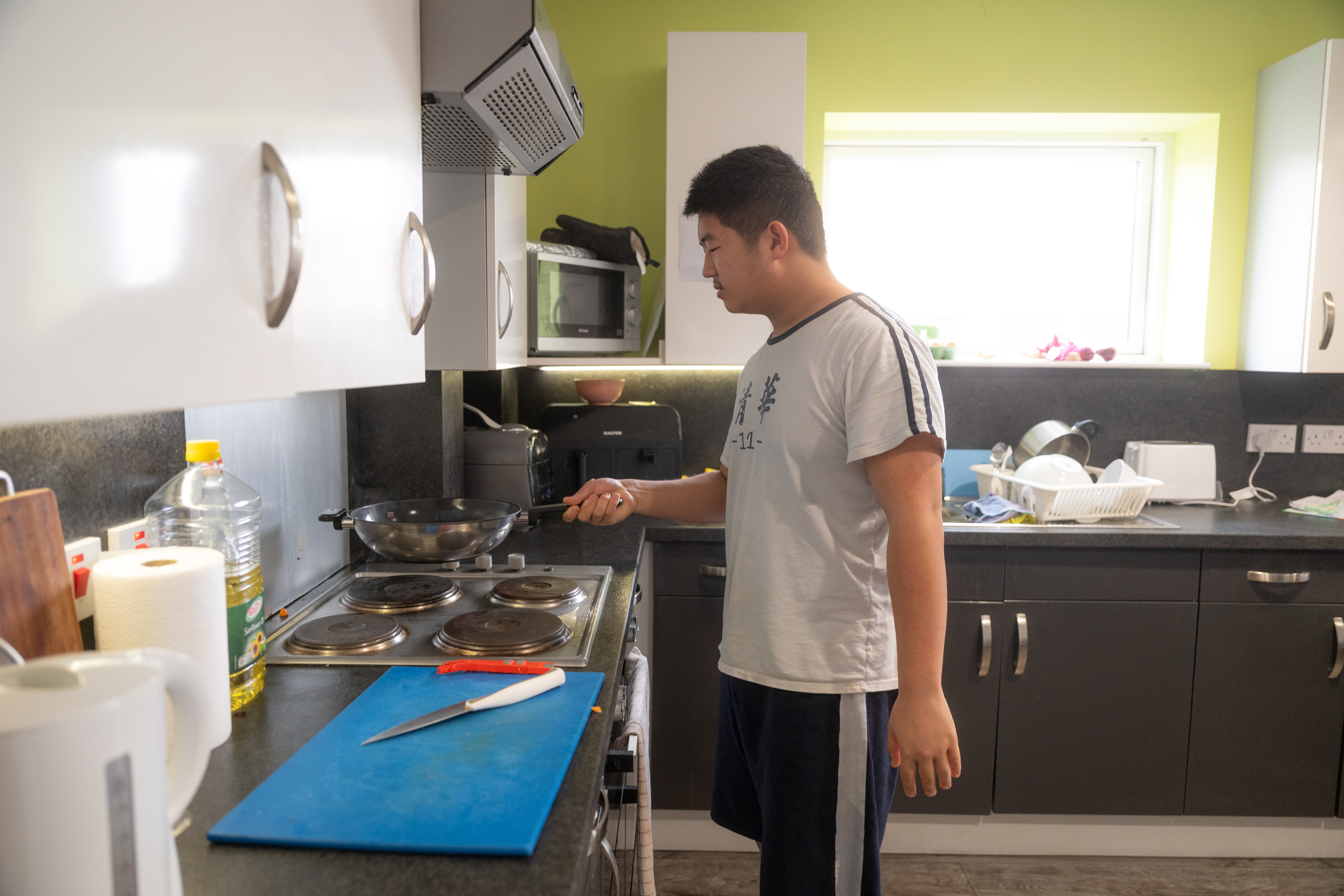 Kitchen: Shared kitchen with dark cabinetry, table and stools, students cooking or seated at the table.