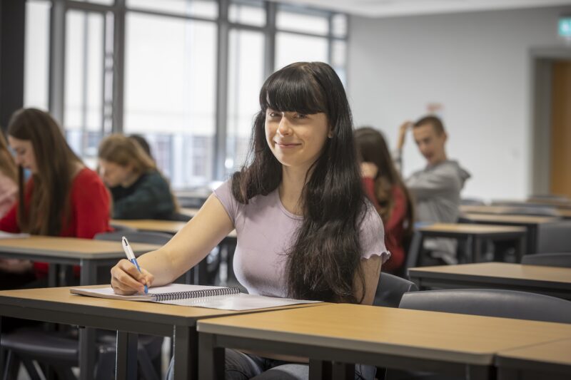 a girl sits at a desk smiling