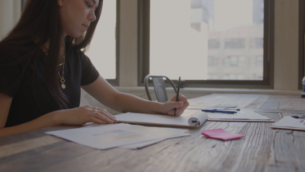 Student studying at a desk surrounded by paper and sticky notes